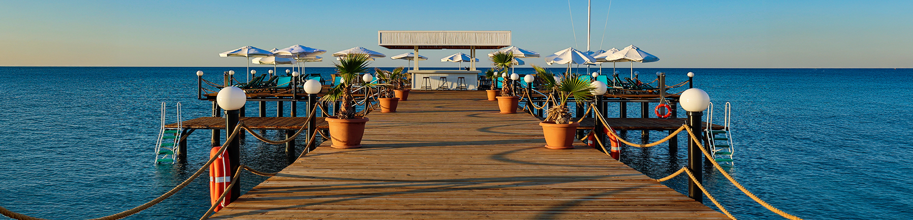 Seebrücke mit Sonnenliegen und Blick auf das ruhige Meer